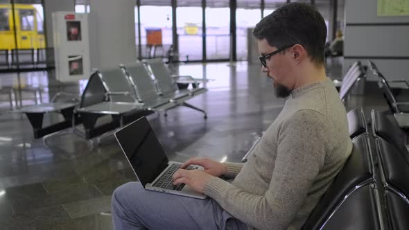 Guy Types on Laptop Sitting in Empty Waiting Room