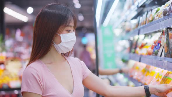 Asian young woman wearing face mask and holding shopping basket in supermarket department store