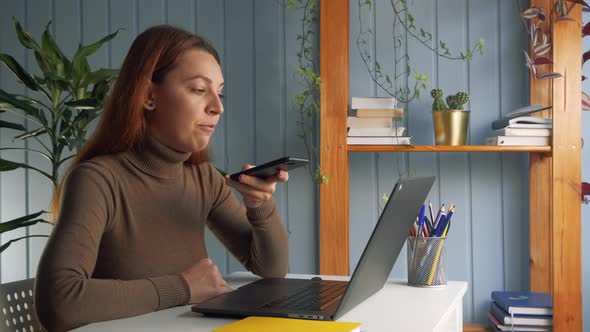 Businesswoman Sitting at Workplace Desk, Hold Smartphone and Call Up with Colleague on Speakerphone