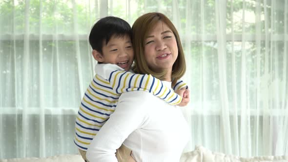 Asian Child On A Piggy Back Ride With His Mother At Home