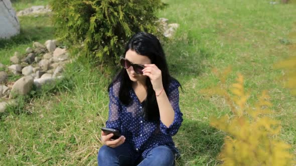Young Brunette Girl in a Denim Jacket She Uses a Smartphone