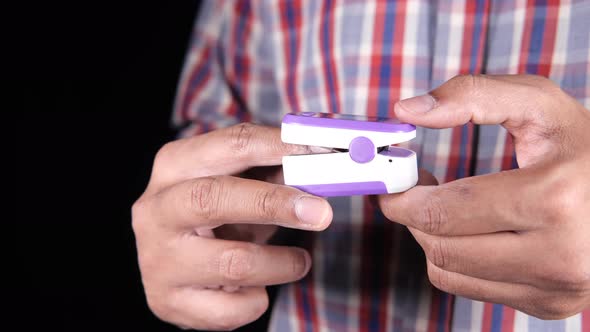 Close Up of Man Hand Using Pulse Oximeter Isolated on Black