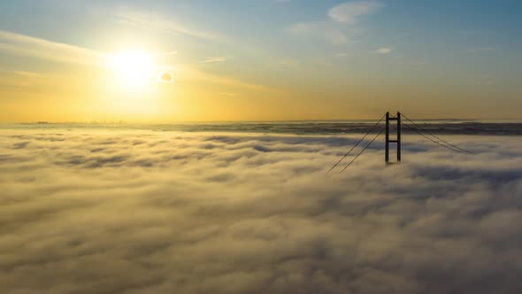 Aerial reveal of the Humber Bridge as the sun is rising with low cloud and fog passing by very quick