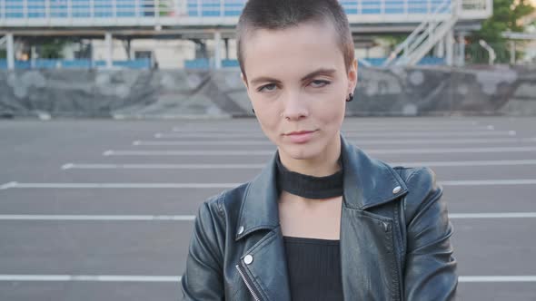 Portrait of Smiling Young Woman with Short Hair in Industrial City Background at Sunset.