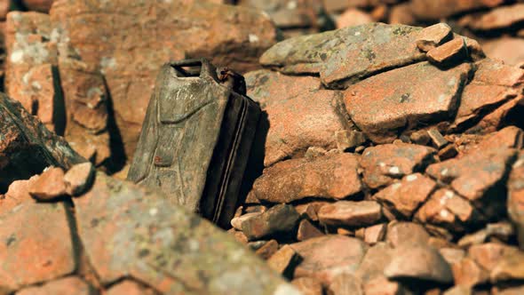 Old Rusty Metal Canister for Gasoline Fuel at Rocks alt