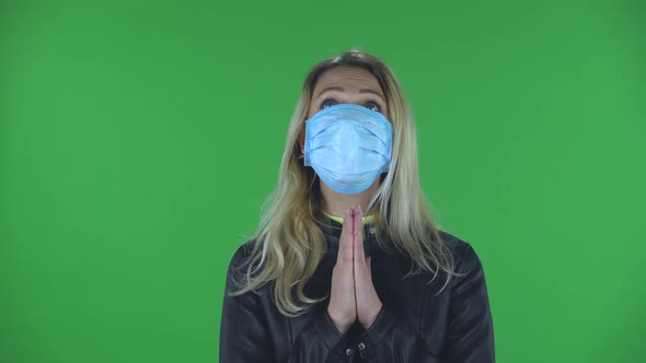 Portrait of Beautiful Young Woman in Medical Mask Is Looking Straight and Prays Clasped Hands Palm