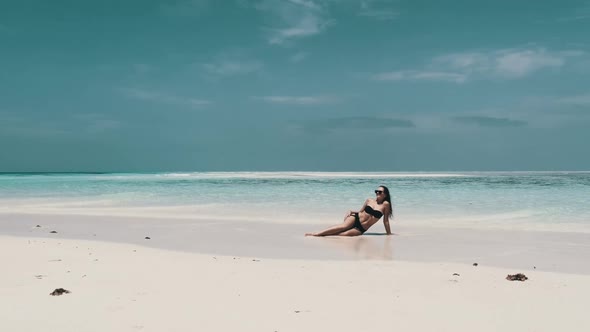 Sexy Woman in Bikini Tans on an Empty Paradise Beach on Island in Ocean Mnemba