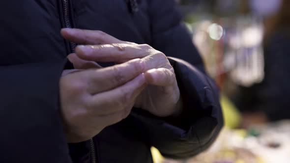 Elderly female in a warm coat trying on a ring