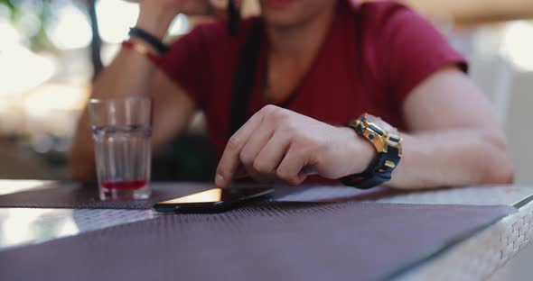 Man Using Mobile Phone Sitting in Outdoor Cafe