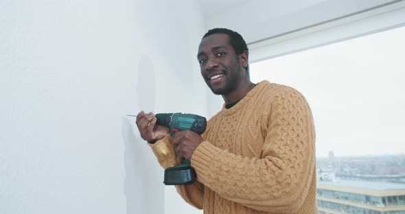 Young black man ready to drill hole into wall of new home