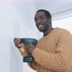 Young black man ready to drill hole into wall of new home - VideoHive Item for Sale