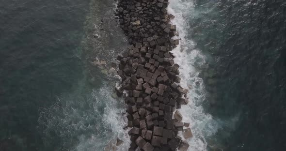 waves crashing over a spit of rocks in the sea. shot on a mavic pro in D-log at 4K