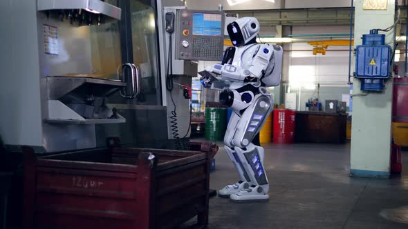 One Droid Checks Machines While Working with a Tablet at a Plant.