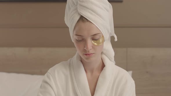 Beautiful Woman Applying Eye Patches after Shower