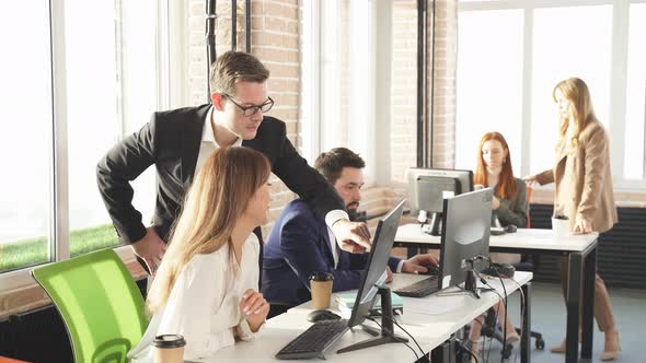 Male Boss Shows His Asian Colleague Something on a Monitor Screen Discussing New Business Ideas