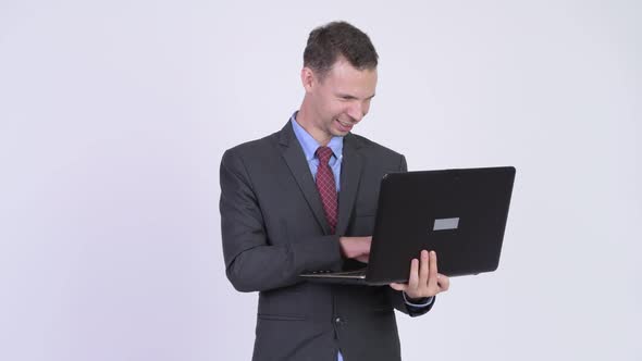 Studio Shot of Happy Evil Businessman Using Laptop