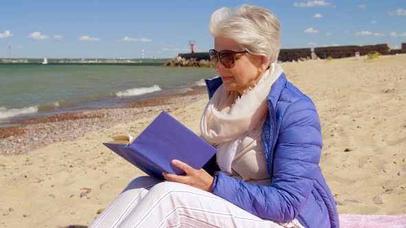 Happy Senior Woman Reading Book on Summer Beach