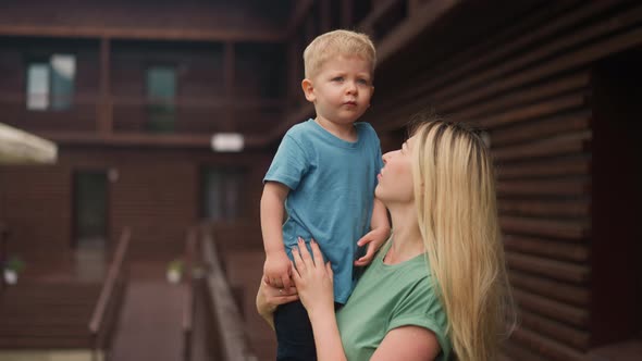 Mother Embraces Little Son on Veranda Deck of Eco Hotel