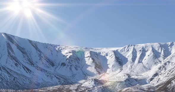 Timelapse of Sun Movement on Crystal Clear Sky Over Snow Mountain Top. Yellow Grass at Autumn Meadow