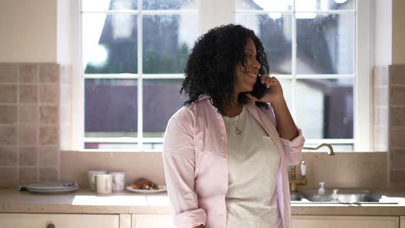 Happy Woman Talking on Phone Walking in Kitchen at Home Indoors