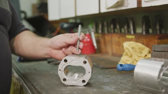 Caucasian male hands factory worker at a factory sitting at a workbench and working on a metal