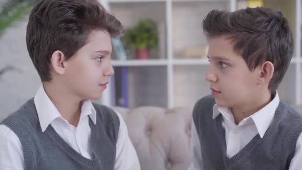 Close-up Side View of Two Identical Twin Brothers Looking at Each Other and Smiling. Stylish