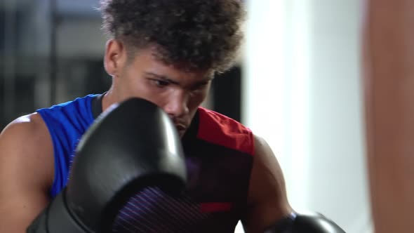 Professional Black Boxer is Striking Punchbag in Boxing Training Center
