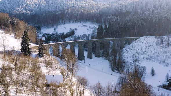 Scenic view of a stone train viaduct in a winter mountain valley,snow.