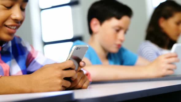 Students using digital tablet and mobile phone in classroom
