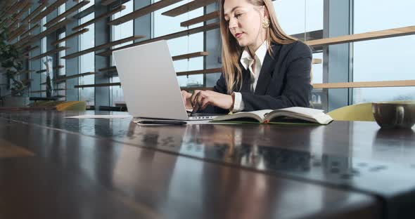 Concerned Woman Working on Laptop Computer and Looking Away Thinking Solving Problem at Office