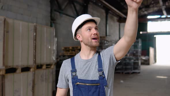 Serious Manager in Helmet and Uniform Giving Commands to Workers on Industrial Warehouse