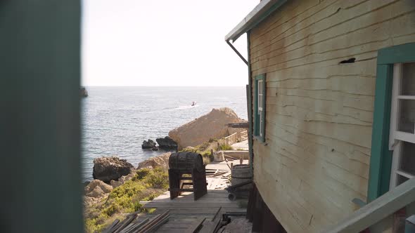 Old wooden house terrace with a keg in a holder on a rocky sea shore.