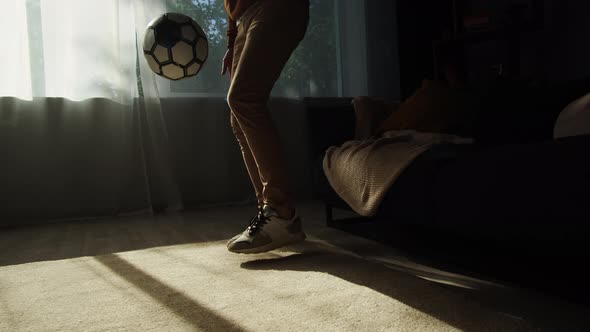 Man Professional Football Player Training and Controlling a Soccer Ball in the Living Room at Home