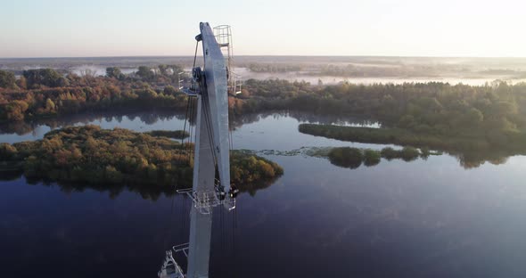 Boom of an Idle Port Crane on the Background of the River at Dawn