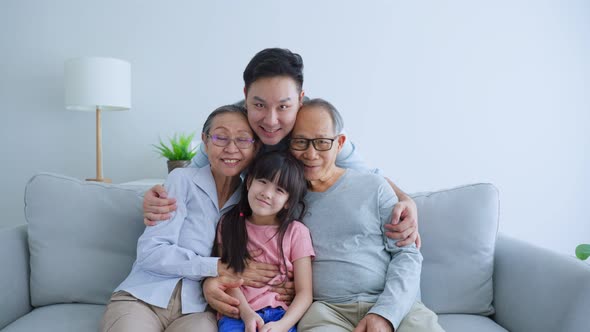 Portrait of Asian muti-generation, family sit on sofa in living room spend time together in house.