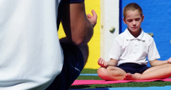 Yoga instructor instructing children in performing yoga