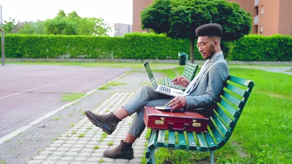4k uhd black man outdoor sitting bench using agenda and computer