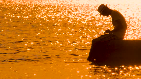 Travel Blogger with Notebook on Sunset. Young Man, Hipster Silhouette on Seascape. Freelancing