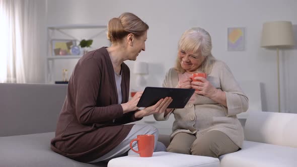 Cheerful Mature Women Scrolling Web-Pages on Tablet and Smiling, Shopping App