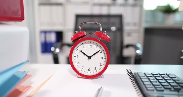 Red Alarm Clock for Ten O'clock with Large Number of Folders is on Table