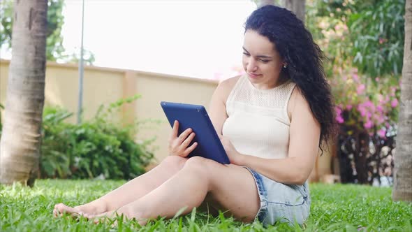 European Woman Makes Use of a Tablet or Phone with a Smartphone, Leafs or Texting with Her Finger