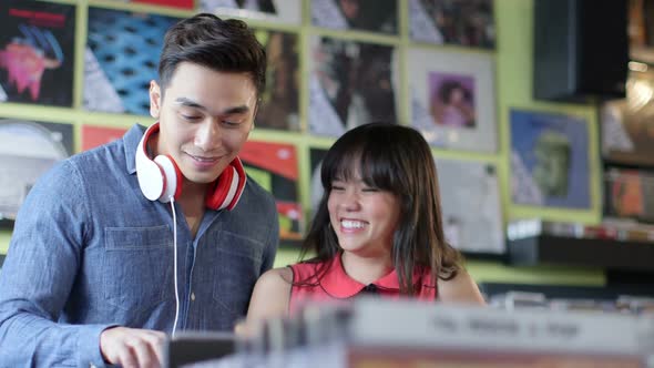 A Young Woman and Young Man happily flick through vintage records together