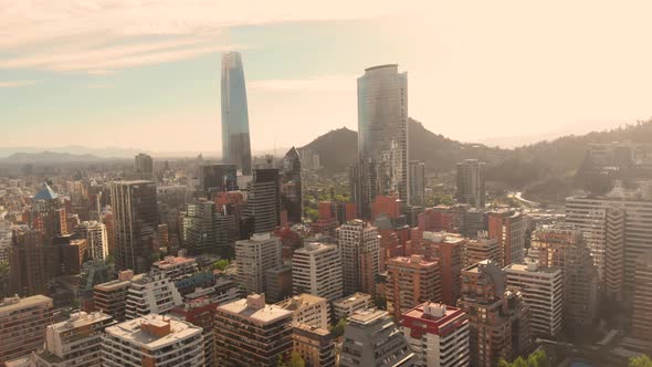 Aerial over concrete jungle flying towards tall skyscrapers on a sunny afternoon, Santiago de Chile-