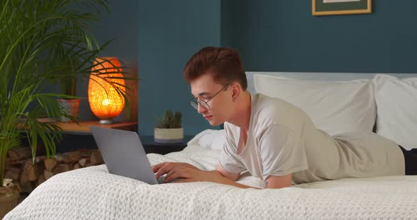 Young man typing chatting on lwith friends or girlfriend typing on a laptop at home
