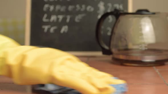 Hands in rubber gloves cleaning down cafe table close up shot