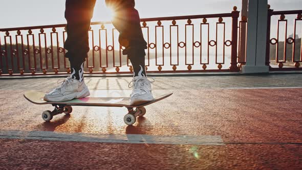 Young Hipster Woman with Pink Hair Wearing Informal Outfit and Glasses is Skateboarding Along