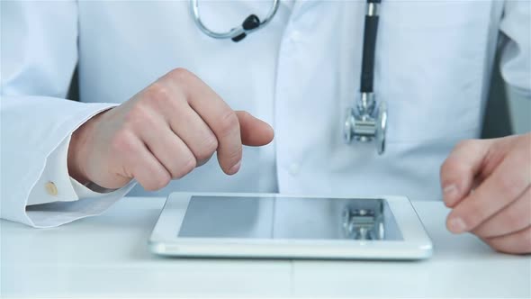 Doctor Sitting In Hospital Office And Using Digital Tablet.