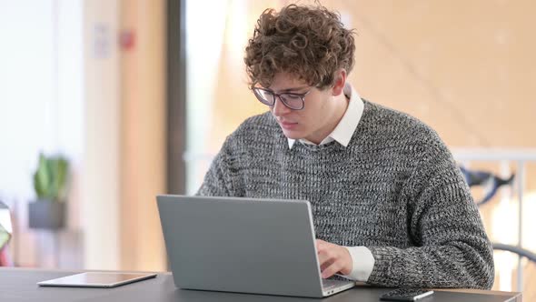 Young Man with Laptop Smiling at Camera