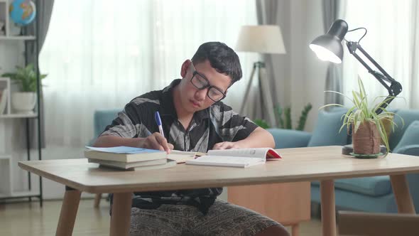 Asian Boy Is Studying At Home, Asia Child Writing While Sitting On The Table