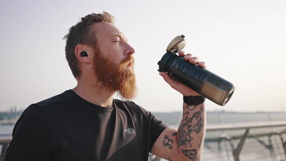 Tired Man Pours Water Into Mouth From Thermos After Running